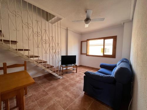 un soggiorno con un divano blu e una scala di Duplex Frente Al Mar a San Pedro del Pinatar