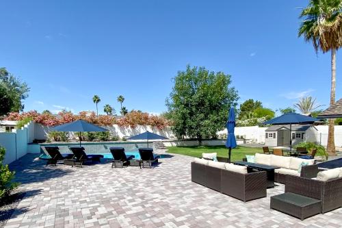 a patio with chairs and tables and umbrellas at 3 Mi to Kierland! Luxe Desert Home with Heated Pool in Scottsdale
