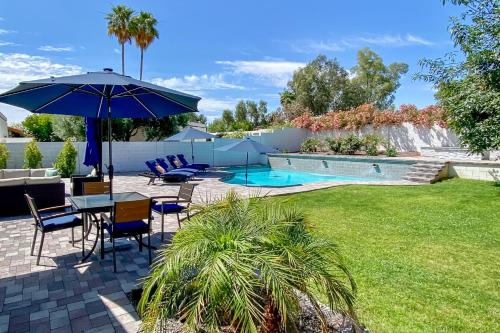 a patio with a table and chairs and an umbrella at 3 Mi to Kierland! Luxe Desert Home with Heated Pool in Scottsdale