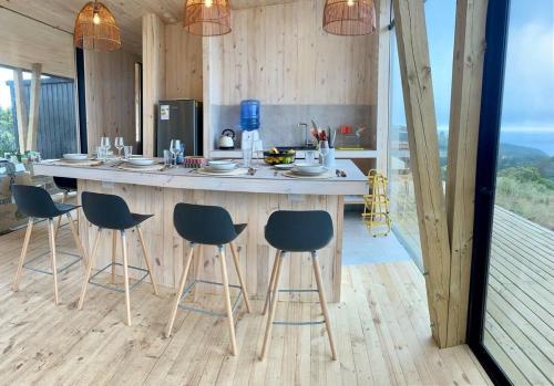 a kitchen with a large island with bar chairs at Olas de Buchupureo: con vida de campo in Cobquecura