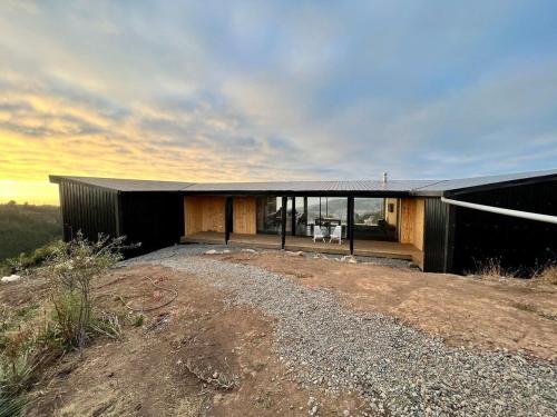 a house with a black roof on top of a hill at Olas de Buchupureo: con vida de campo in Cobquecura