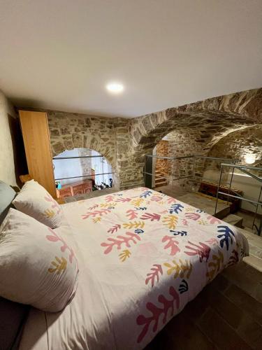 - un grand lit dans une chambre dotée d'un mur en pierre dans l'établissement April' House Neffiès, à Néffiès