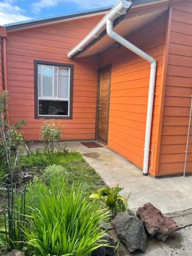 a house with an orange wall and a door at Cabaña Andrea in Curacautín