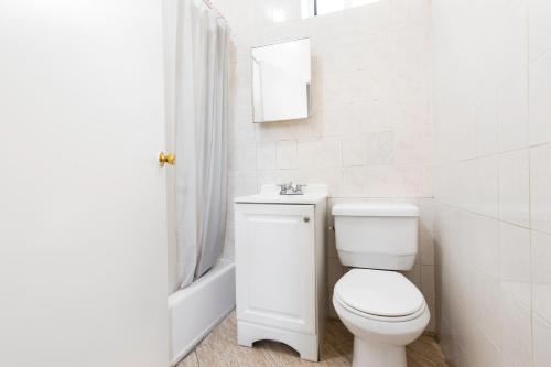 a white bathroom with a toilet and a sink at Prime Location Upper Manhattan Furnished Apartment in New York