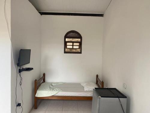 a small bedroom with a bed and a tv at Raízes Pousada in Porto Seguro