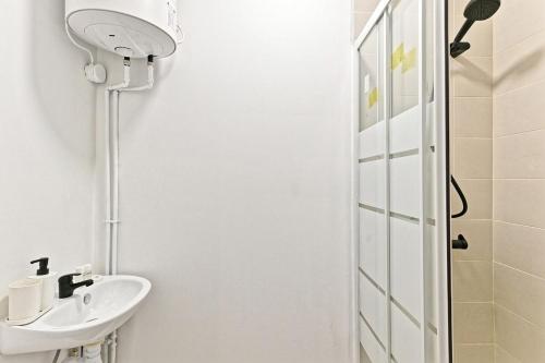 une salle de bain blanche avec une douche et un lavabo dans l'établissement Studio situé dans le 11ème arrondissement, à Paris