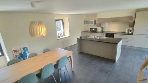 une cuisine avec une grande table en bois et des chaises bleues dans l'établissement Maison de famille entre campagne et océan, Bretagne Trévignon, à Trégunc