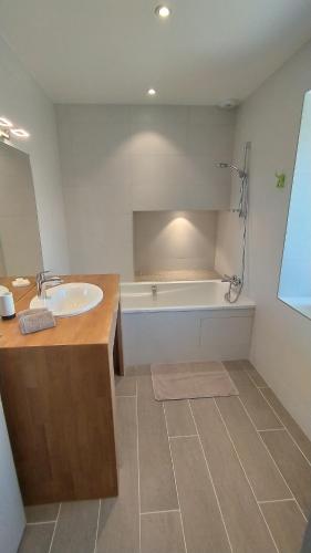une salle de bain avec un lavabo et une baignoire dans l'établissement Maison de famille entre campagne et océan, Bretagne Trévignon, à Trégunc