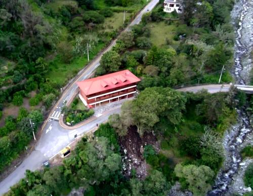 a building with a red roof next to a road at The Lookout Hideaway in Baños