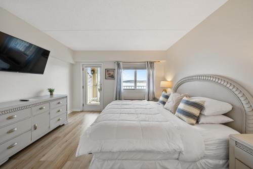 a white bedroom with a large bed and a television at Bella Vista Suites Lake Geneva in Lake Geneva