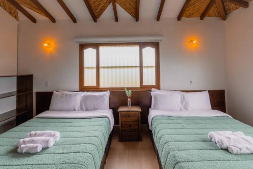 two beds in a room with towels on them at Artemisa Hotel Villa de Leyva in Santa Sofía