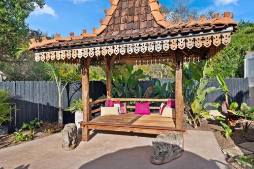 a wooden gazebo with pink pillows in a garden at Jasmine Hideaway and Newly Renovated in Summerland