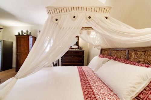 a bedroom with a canopy bed with white sheets at Appartamento Holly House in Radda in Chianti
