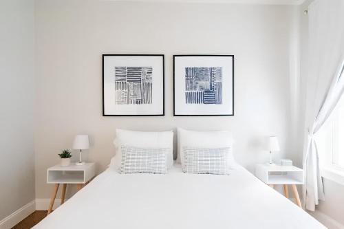 a white bedroom with two pictures on the wall at Jennifers Private Apartment with Outdoor Patio in Providence