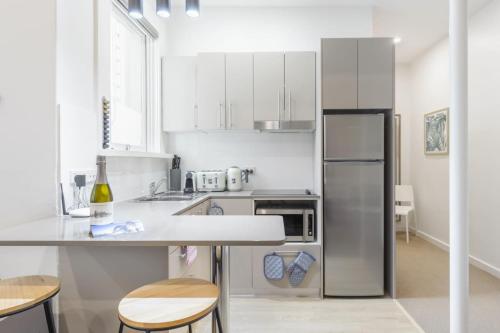 Una cocina con gabinetes blancos y un refrigerador de acero inoxidable. en Huge Designer Studio Next to Lovely Park, en Sídney