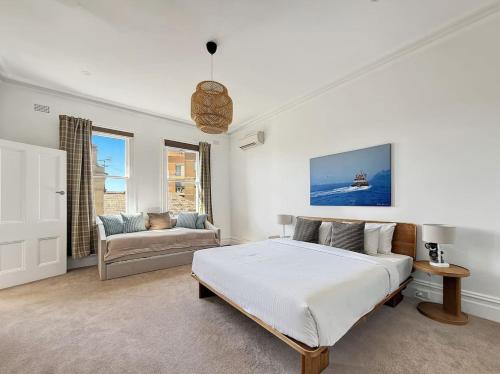 a white bedroom with a bed and a couch at Serviced Luxury Condo, Parkside, moments to metro in Sydney