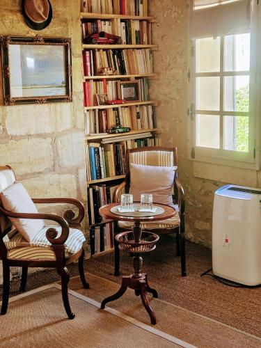 une chambre avec deux chaises, une table et une étagère à livres dans l'établissement La Maison Colline, à Saint-Émilion