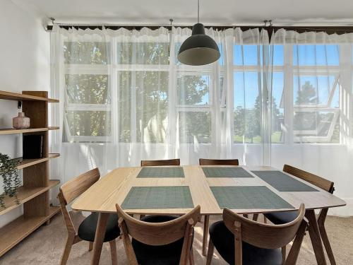 a dining room table with chairs and a large window at Serviced Luxury Condo, Parkside, moments to metro in Sydney
