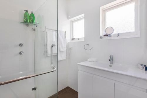 a white bathroom with a shower and a sink at Stunning Huge Studio, Sunny terrace with Parking in Sydney