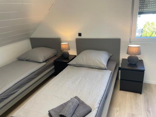 zwei Einzelbetten in einem Zimmer mit zwei Lampen in der Unterkunft Blauer Stein 07 Haus in Pulheim