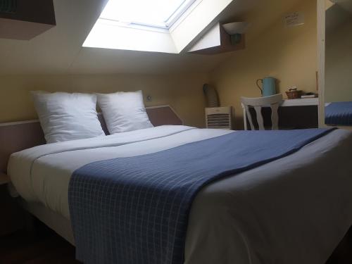 a bedroom with a bed with a blue blanket and a window at Hôtel Restaurant Aux Deux Roses in Neuf-Brisach