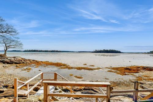 a wooden bench sitting on a beach near a body of water at By the Sea in South Freeport