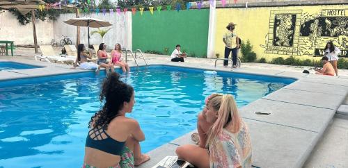 a group of women sitting around a swimming pool at Hostel Treebu in Valladolid