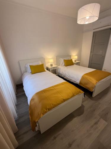 two beds with yellow pillows in a room at Casa Santos in Sardoal