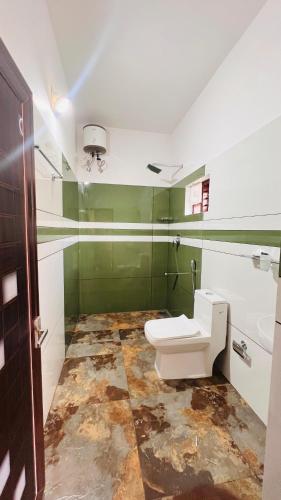 a bathroom with a white toilet and green walls at Wayanad Haven Villa in Wayanad