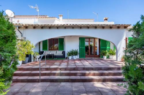 ein weißes Haus mit einer Terrasse und einer Treppe in der Unterkunft Casa Tritons in Port d'Alcúdia