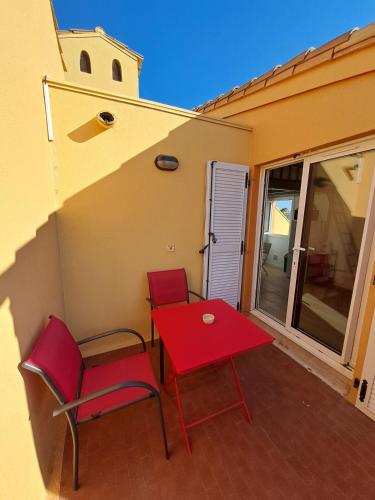 d'une table rouge et de deux chaises sur un balcon. dans l'établissement 4 Soleil - Mezzanine Wifi Clim Plage Parking, au Cap d'Agde