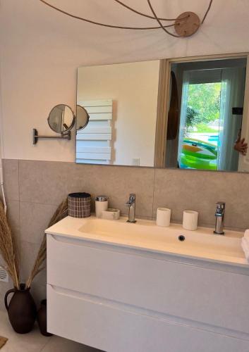 une salle de bain avec un lavabo et un miroir dans l'établissement Villa Fiori Porto Vecchio avec piscine privée, à Porto-Vecchio