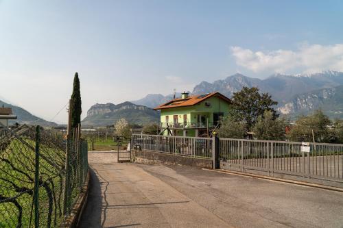 a house behind a fence with mountains in the background at La Casa nel Verde in Arco