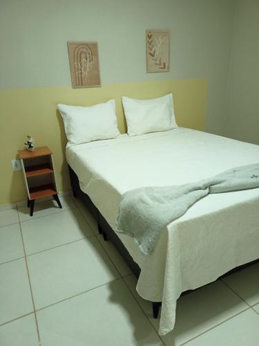 a bedroom with a bed with white sheets and a night stand at NORTE HOTEL Guaraciaba in Guaraciaba do Norte