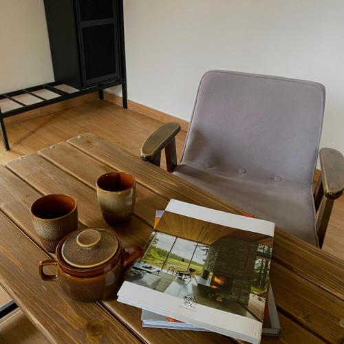 a table with cups and a book and a chair at Centrum Łąkowa 1 in Wünschelburg