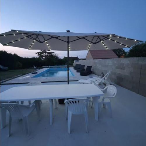 une table et des chaises avec un parasol à côté d'une piscine dans l'établissement Maison 12 pers avec piscine 