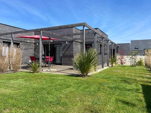 a black house with a red table in a yard at Villa Egurra, à proximité d'une plage de sable fin in Santec
