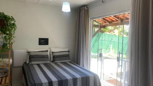 a bedroom with a bed and a large window at Recanto dos Dinos - Apto Térreo in Paty do Alferes