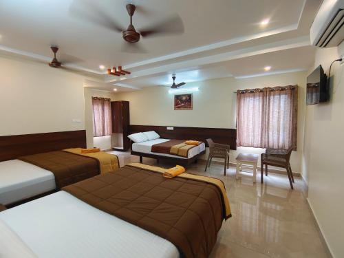 a bedroom with two beds and a living room at Hotel DKR Grand in Tirupati
