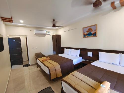 a hotel room with two beds and a bathroom at Hotel DKR Grand in Tirupati