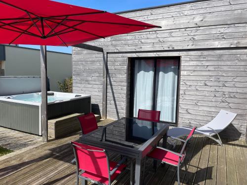 a patio with a table and chairs and a red umbrella at Villa Egurra, à proximité d'une plage de sable fin in Santec