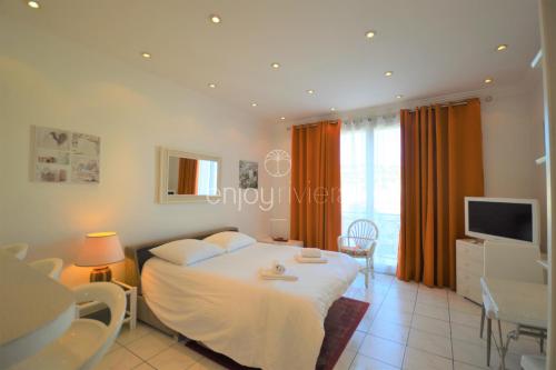 une chambre avec un lit et une télévision dans l'établissement Palais Miramar - Suite White Jardin - 20m Plage, à Cannes