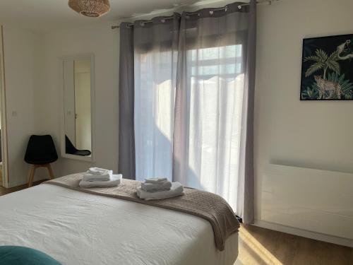 a bedroom with a large window with towels on a bed at Villa Egurra, à proximité d'une plage de sable fin in Santec