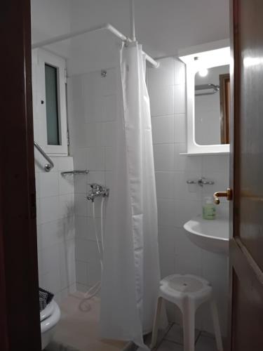 a white bathroom with a shower and a sink at Heliotopos Apartments in Tolo
