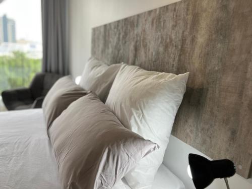 a bed with white pillows and a wooden headboard at One Rosebank in Johannesburg
