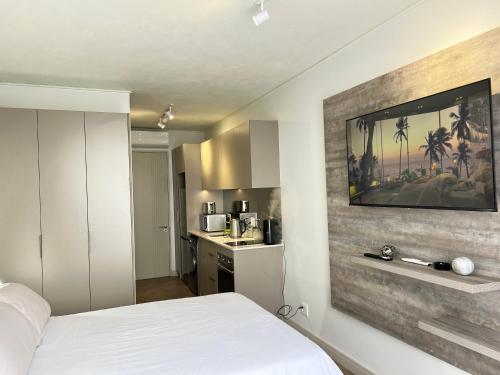 a bedroom with a white bed and a wall with a television at One Rosebank in Johannesburg