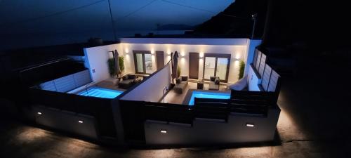 a house with a swimming pool at night at BLU Faflagkos Bay Luxury Suites in Psari Forada