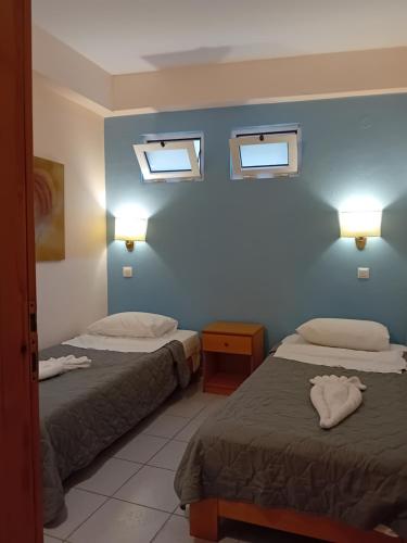 a hotel room with two beds and two windows at Heliotopos Apartments in Tolo
