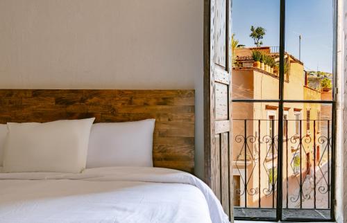 a bedroom with a bed and an open window at Casa Xaca in San Miguel de Allende