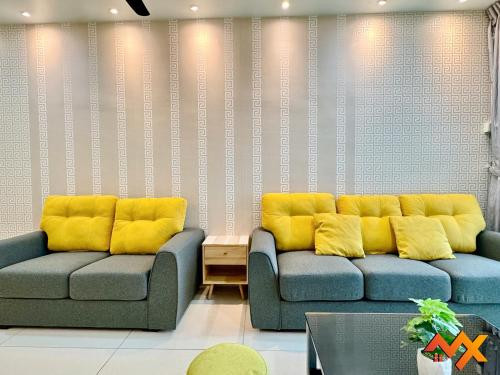 two couches in a living room with yellow cushions at KSL City Mall 6-20pax Private Lift-Netflix-SmartTV 70inch in Johor Bahru